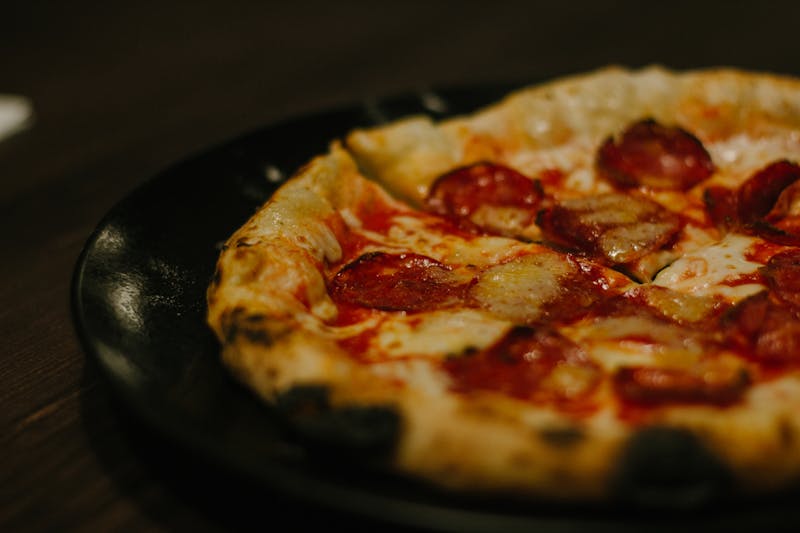 Chef hand-stretching fresh pizza dough in the kitchen